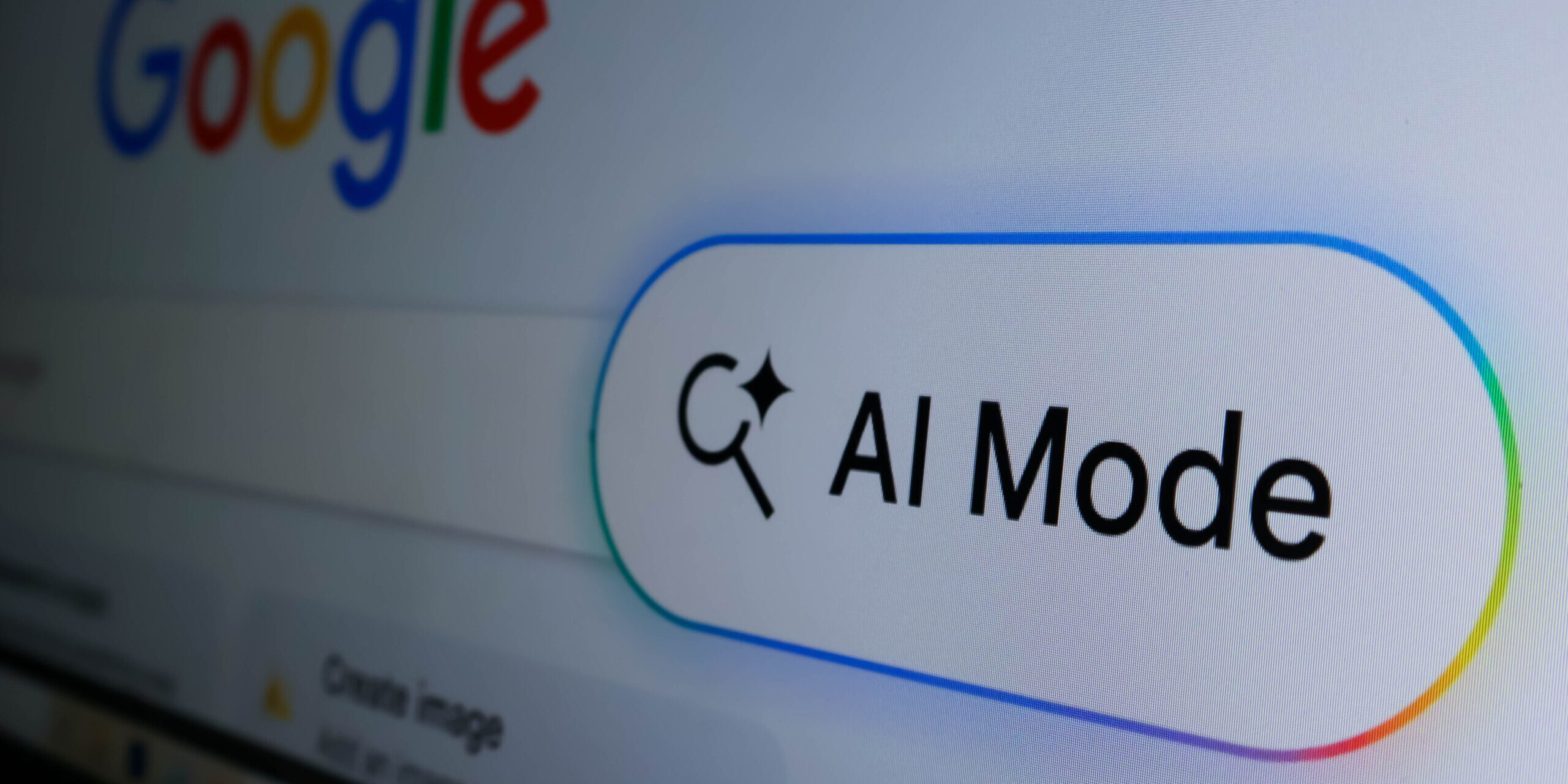 Closeup of a computer screen showing a google search bar with an ai mode button and a colorful glowing border AI search Mode
